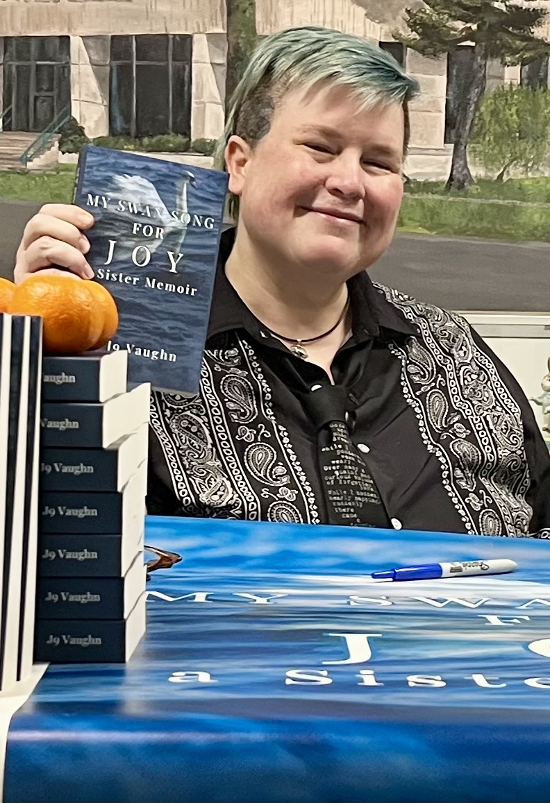 blue haired j9 holding memoir with oranges in the foreground.